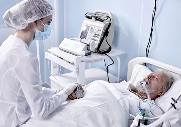 Nurse holding a patient's hand in an ICU